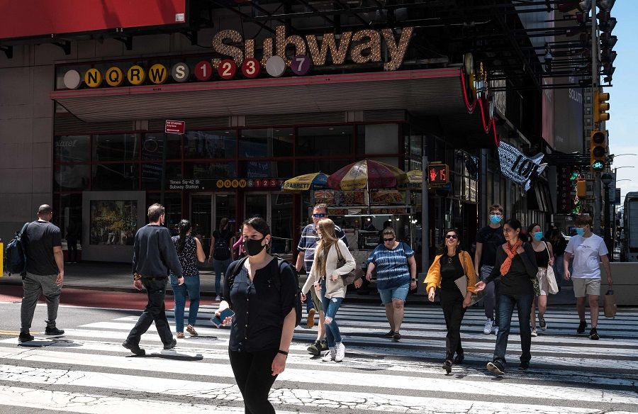 People walk past a subway stop sign on 17 May 2021 in New York City, US. (Angela Weiss/AFP)