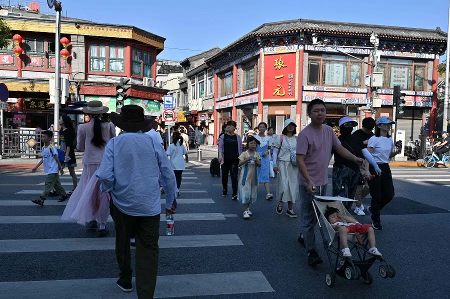 People cross a street in Beijing on 29 August 2024. (Adek Berry/AFP)