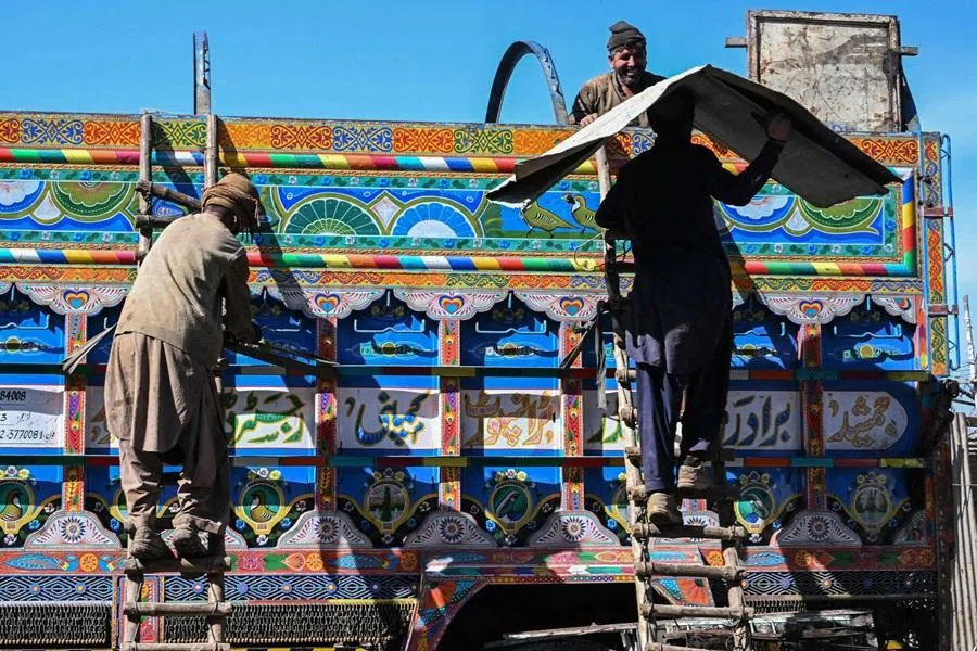 Workers load scraps onto a truck at a scrapyard on the outskirts of Islamabad on 12 February 2026. (Farooq Naeem/AFP)