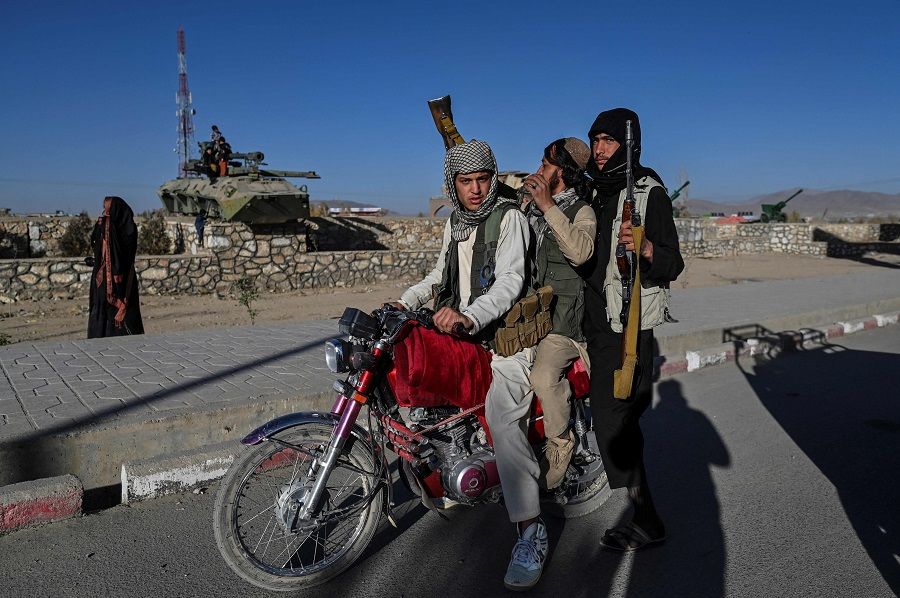 In this picture taken on 13 November 2021, Taliban fighters stop next to destroyed armoured vehicles displayed along a road in Ghazni, Afghanistan. (Hector Retamal/AFP)