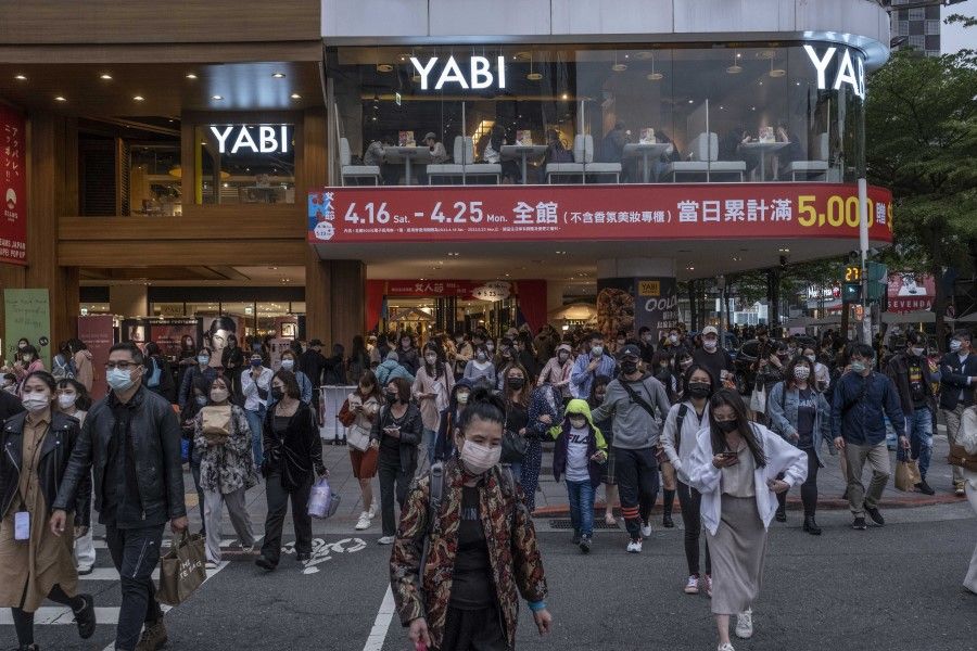Pedestrians wearing protective masks cross a street in a shopping district in Taipei, Taiwan, on 16 April 2022. (Lam Yik Fei/Bloomberg)