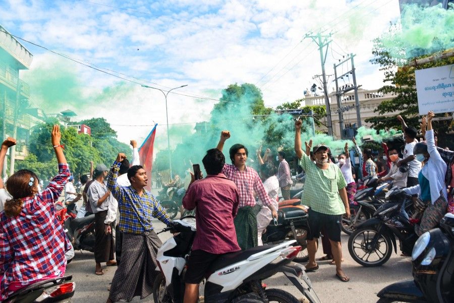 This photo taken and received courtesy of an anonymous source via Facebook on 21 June 2021 shows protesters, some holding flares, taking part in a demonstration against the military coup in Monywa, Sagaing region. (Handout/Facebook/AFP)