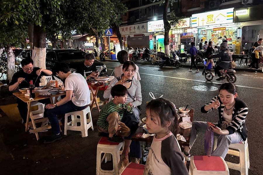 People dine near a restaurant by a street in Chengdu, Sichuan province, China, on 12 April 2024.  (Tingshu Wang/Reuters)