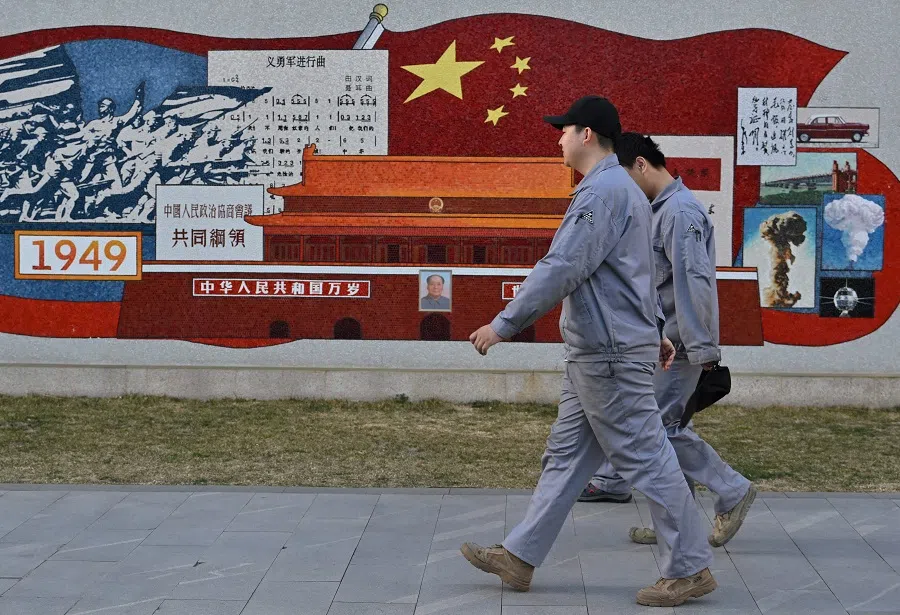 People walk past a mural depicting the history and development of the country at Zhongguancun No 1, an incubation platform for tech companies, in Haidian district in Beijing, China, on 19 March 2025. (Adek Berry/AFP)