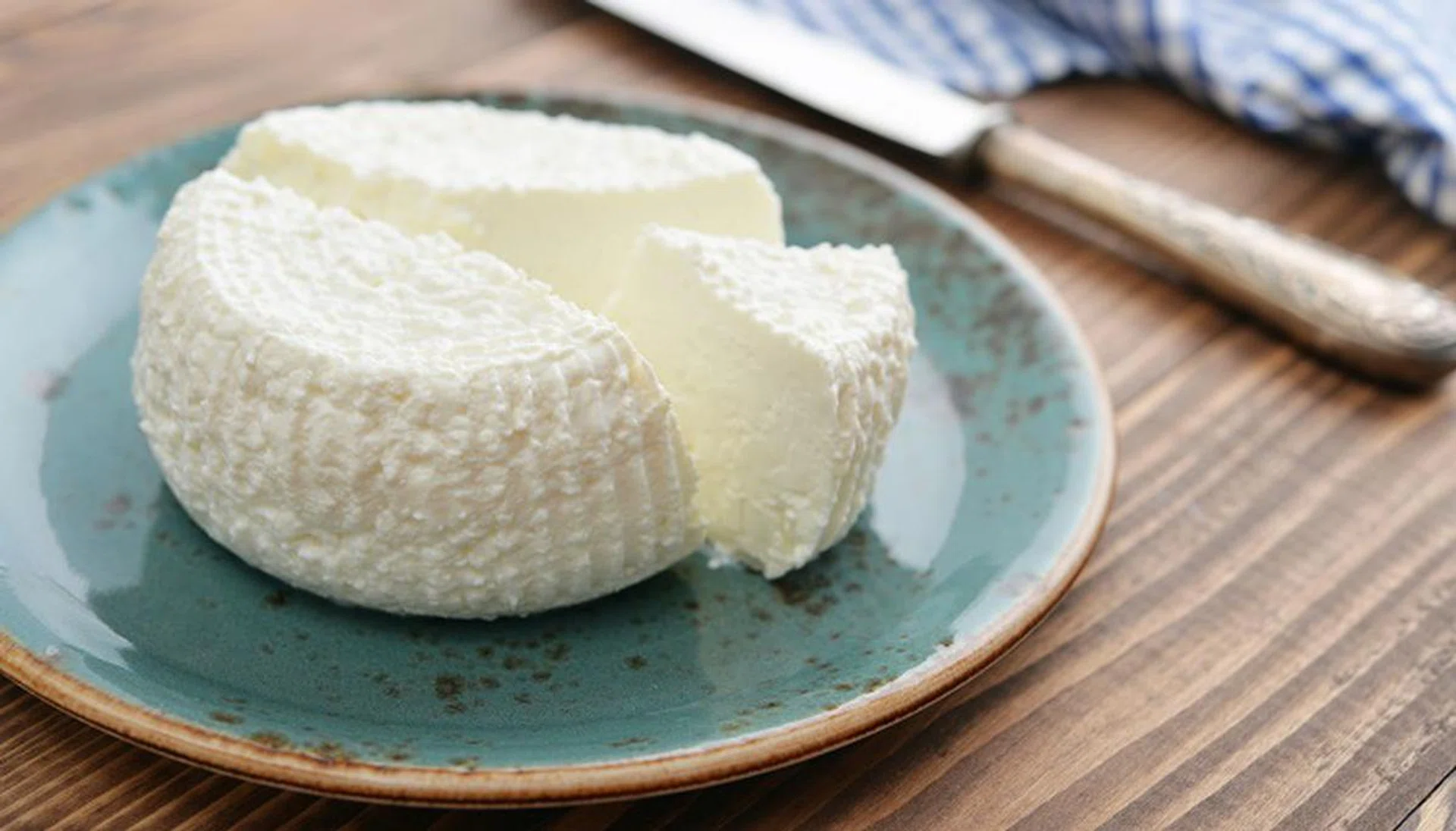 61783428 - fresh ricotta on plate on wooden background