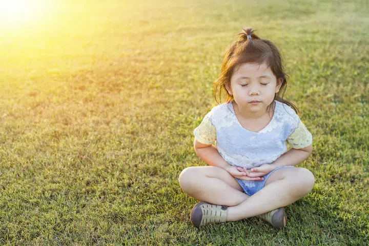 Asian Thai little Cute Girl Making Meditation and Practicing Yoga in Garden with Morning Light Beam.