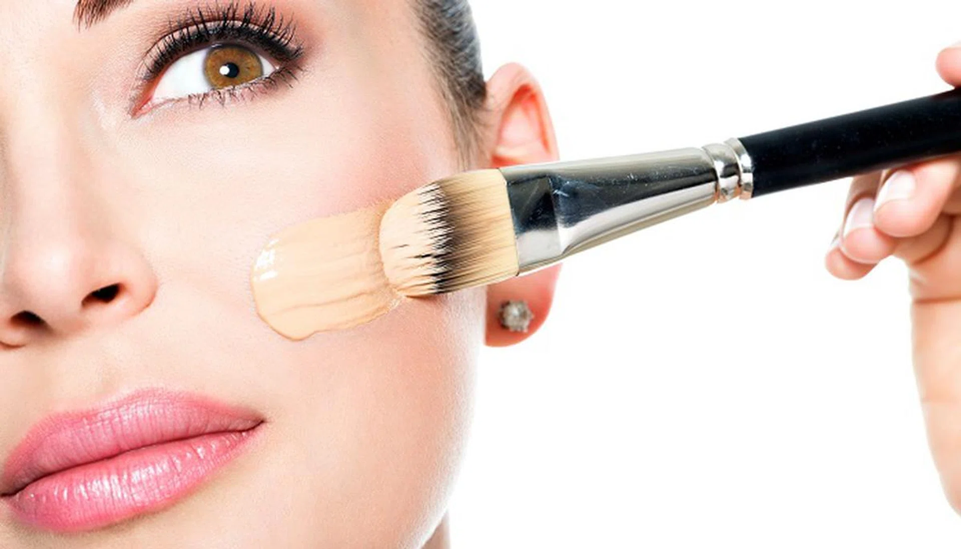 Makeup artist applying liquid tonal foundation  on the face of the woman