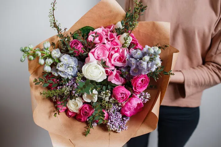 Rich bunch of pink eustoma and roses flowers, green leaf in hand Fresh spring bouquet. Summer Background