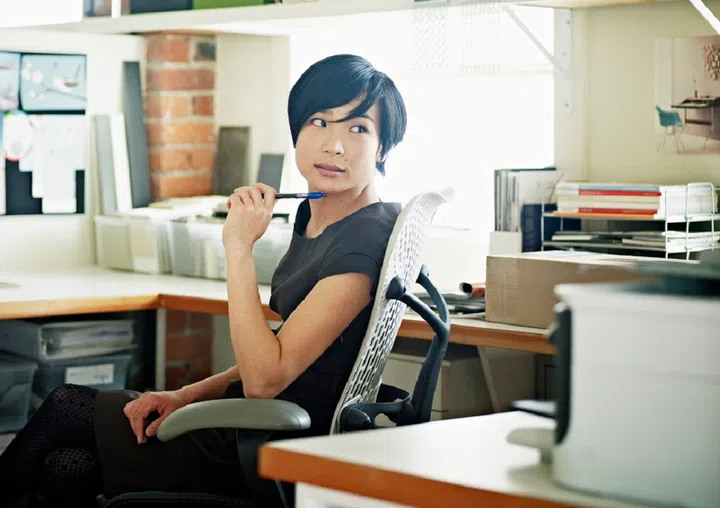 Female designer at desk in office head turned to look at computer