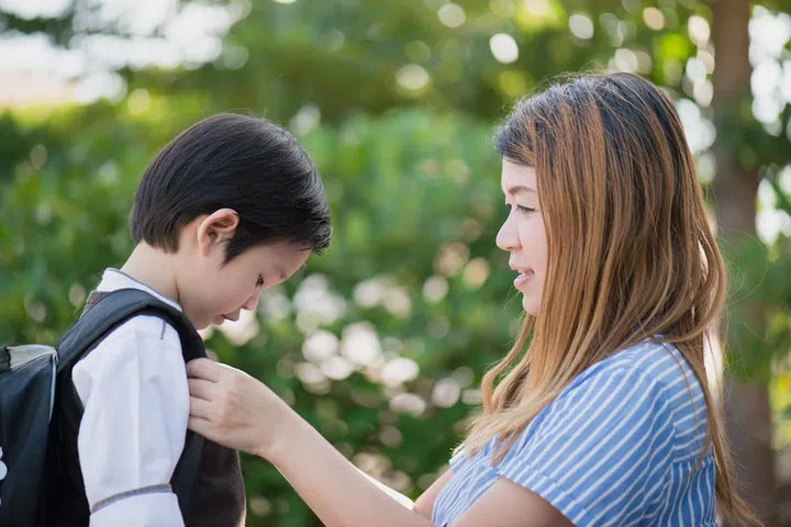 61507574 - asian mother  saying goodbye to her son as he leave for school,back to school concept