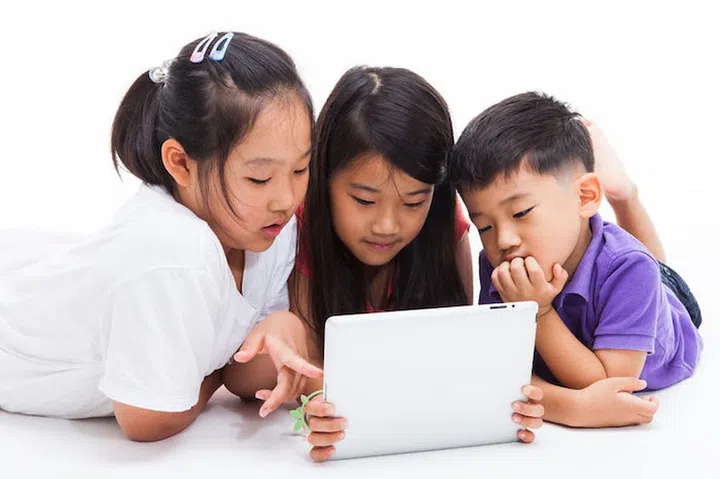 35512634 - three asian kids using a tablet pc isolated on white.