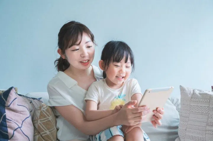 Mom and daughter sitting on a sofa and operating a tablet device