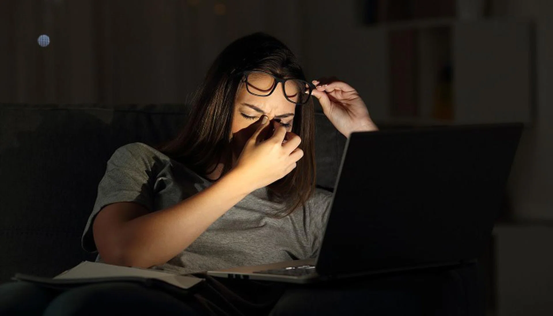 Tired woman suffering eyestrain studying in the night with a laptop at home