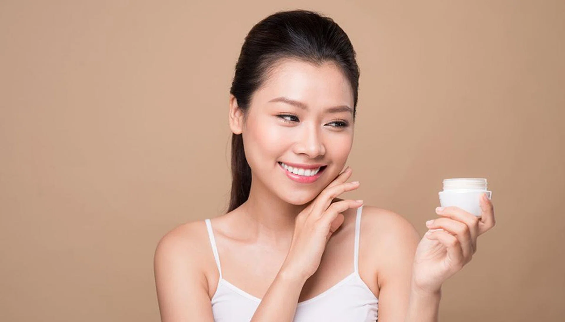 Skincare. Beautiful asian woman show moisturizer or lotion product.