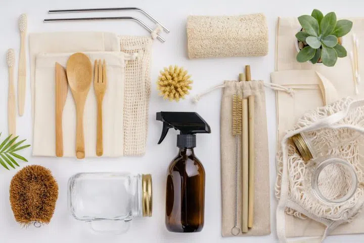 Natural color eco bags, reusable metal and bamboo straws, glass jars, wooden knifes and forks, zero waste cleaning and beauty products, flat lay