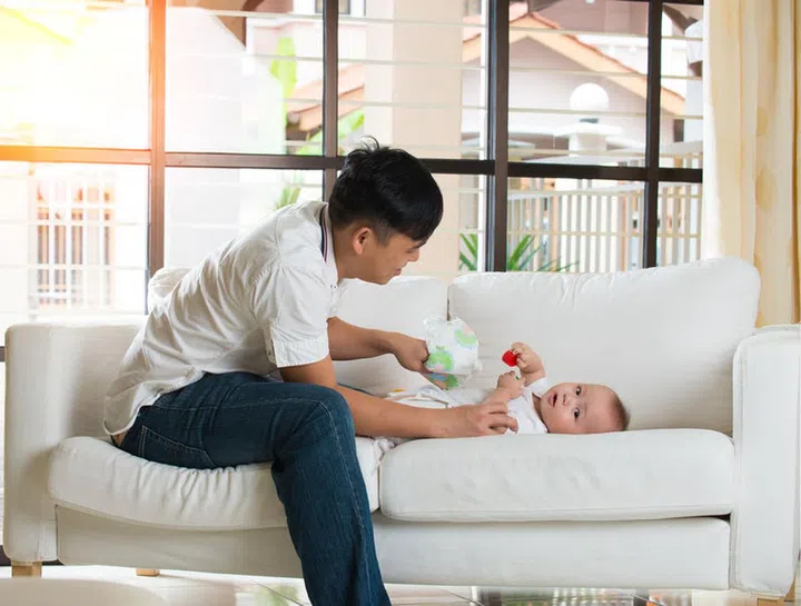 asian father having trouble chaging diaper