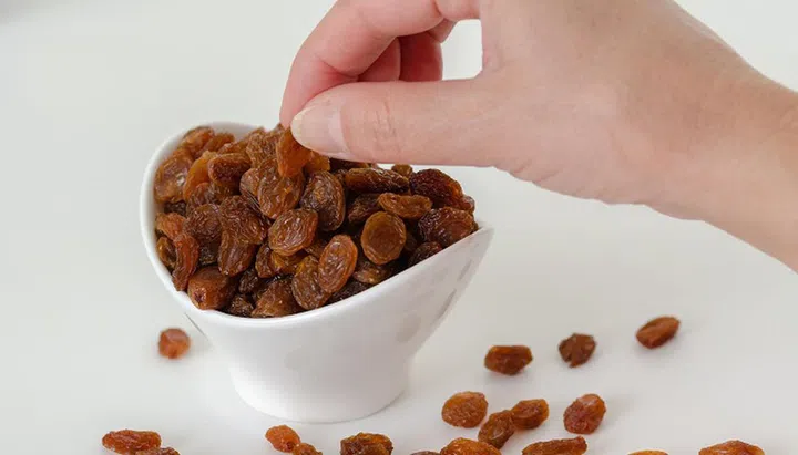 woman is taking raisins from the white bowl.