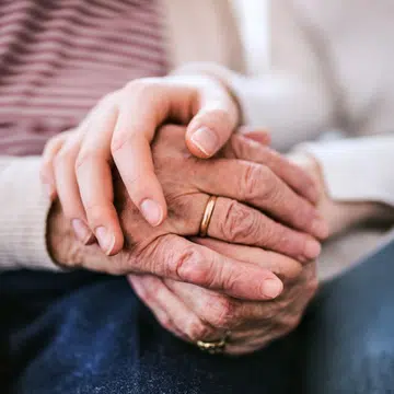 women holding hands with her very elderly mother