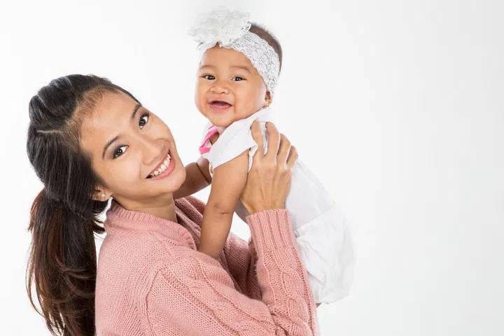 Asian woman holding her baby girl isolated over white background