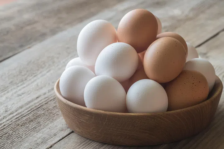 Wooden bowl of raw chicken eggs