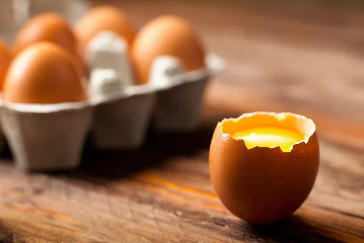 12432310 - opened egg shell with yolk on wood
