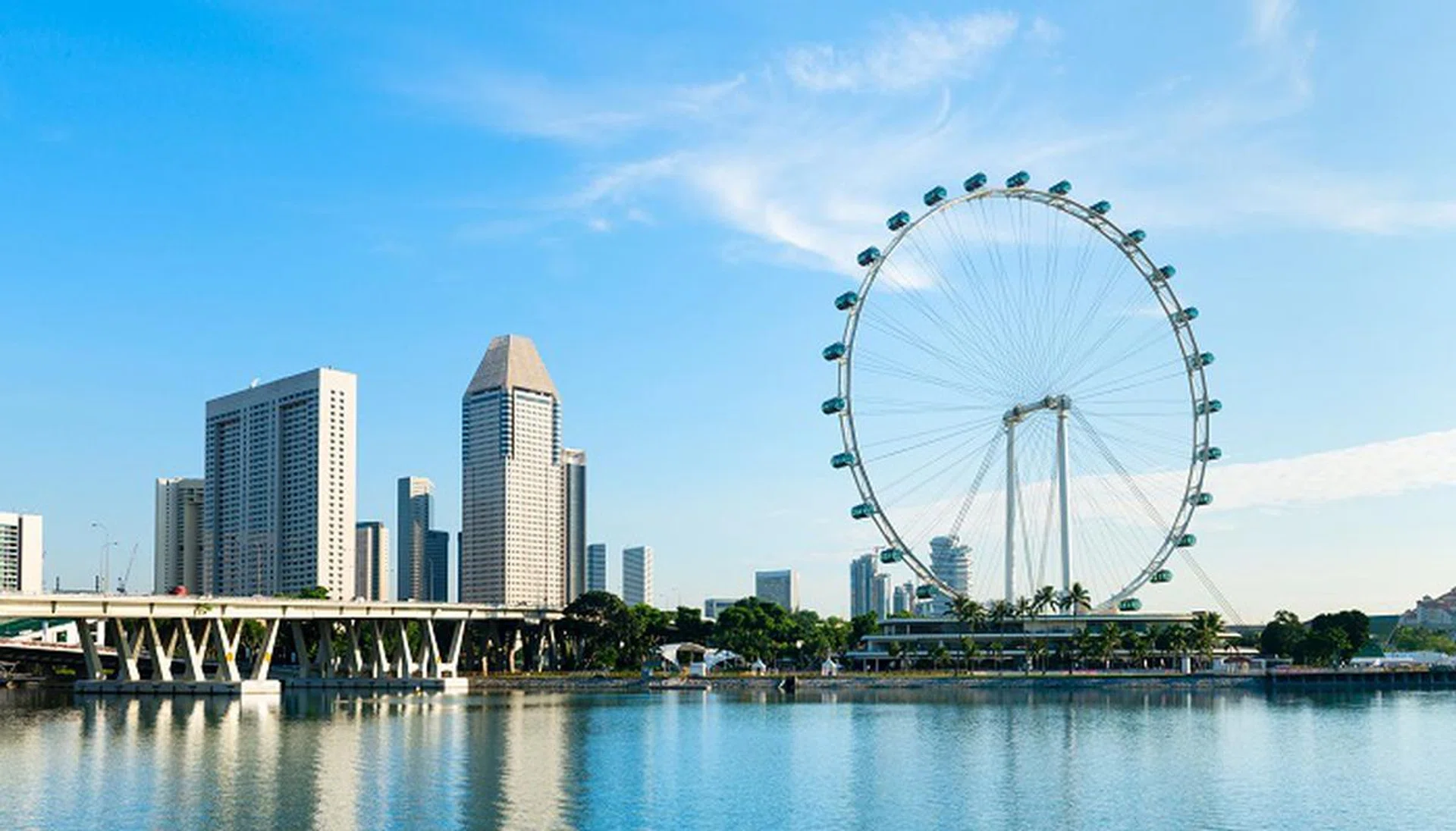 Big ferris wheel in the modern city skyline and bay water on front, Singapore. 