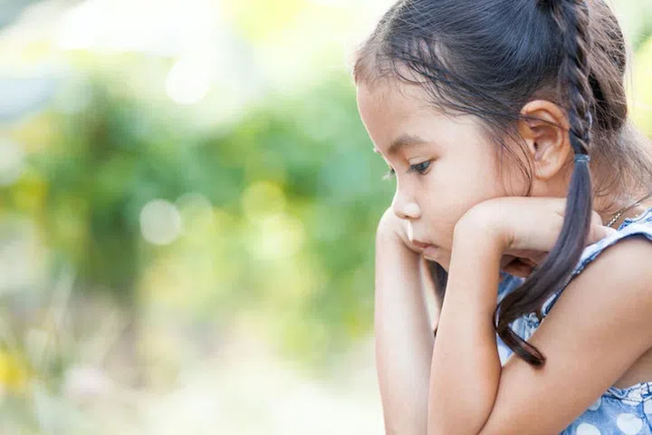 Cute asian little child girl rest her chin on her hands with bored feeling in outside in vintage color tone