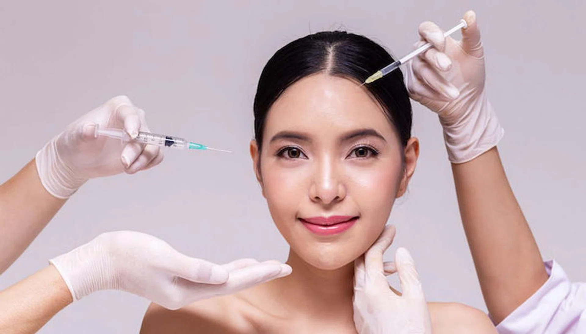 Mixed Asian young 20s woman going through skin care and aesthetic medical therapy and to be injected by hands of doctor with syringes in white background