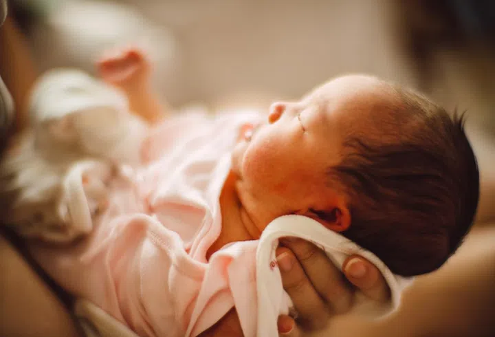 Mom holding her adorable beautiful newborn baby at home under warm sun light