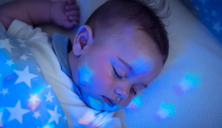 Portrait of nice sleeping baby boy, pretty child resting in his bed, star-shaped night light, healthy and peaceful childhood, new life concept