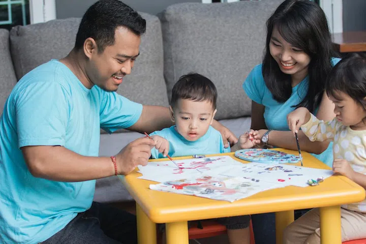 happy little asian kid painting and drawing at home using water color paint