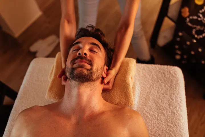 Close up shot of a young man enjoying a head massage at a spa