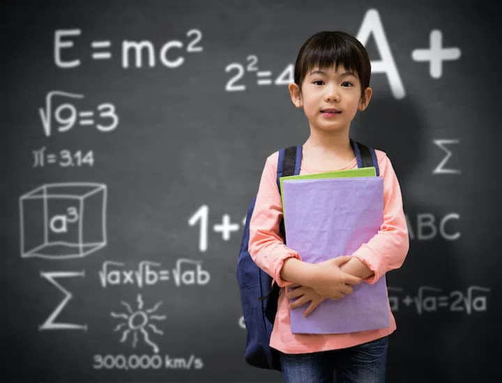 Cute pupil looking at camera holding notepad  against black background