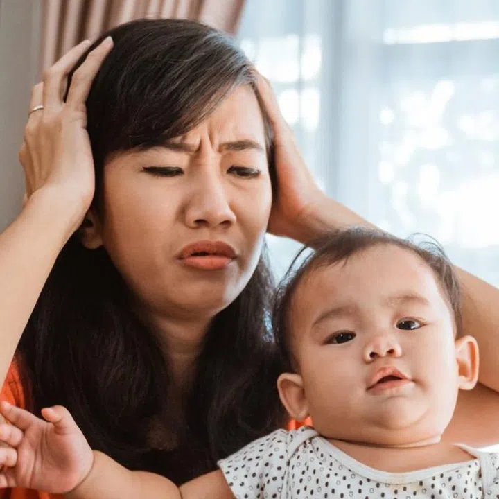 asian young woman working while taking care of her children at home