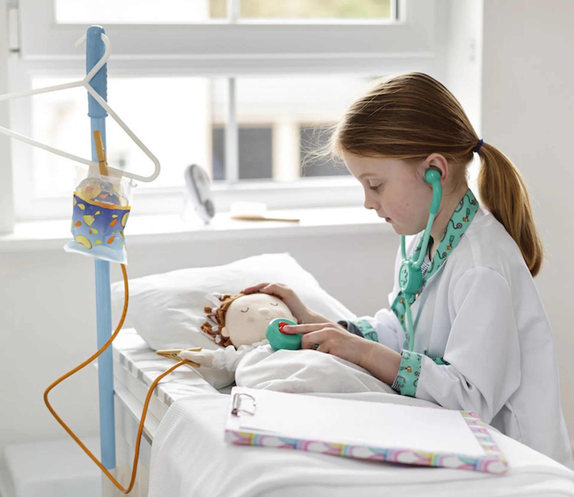 Young girl dressed as doctor pretending to treat patient in make-bleieve hospital bed