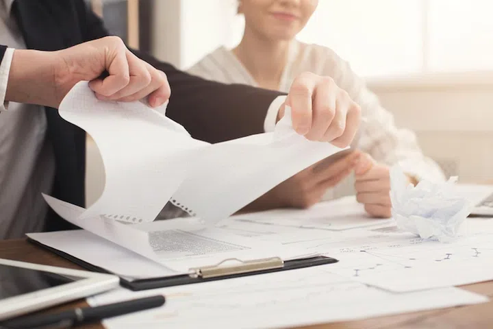 Angry businessman tearing up a document, contract or agreement in office, copy space. Closeup of man hands, selective focus