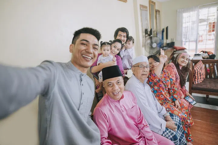 Malaysian malay family taking selfie photo looking at camera waving at home celebrating hari raya