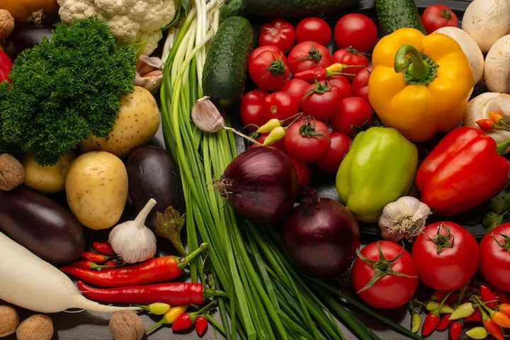 Fresh vegetables and nuts on a brown wooden background