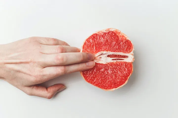 Sexual and female genital concept. Grapefruit and women's fingers like vagina and clitoris symbol.