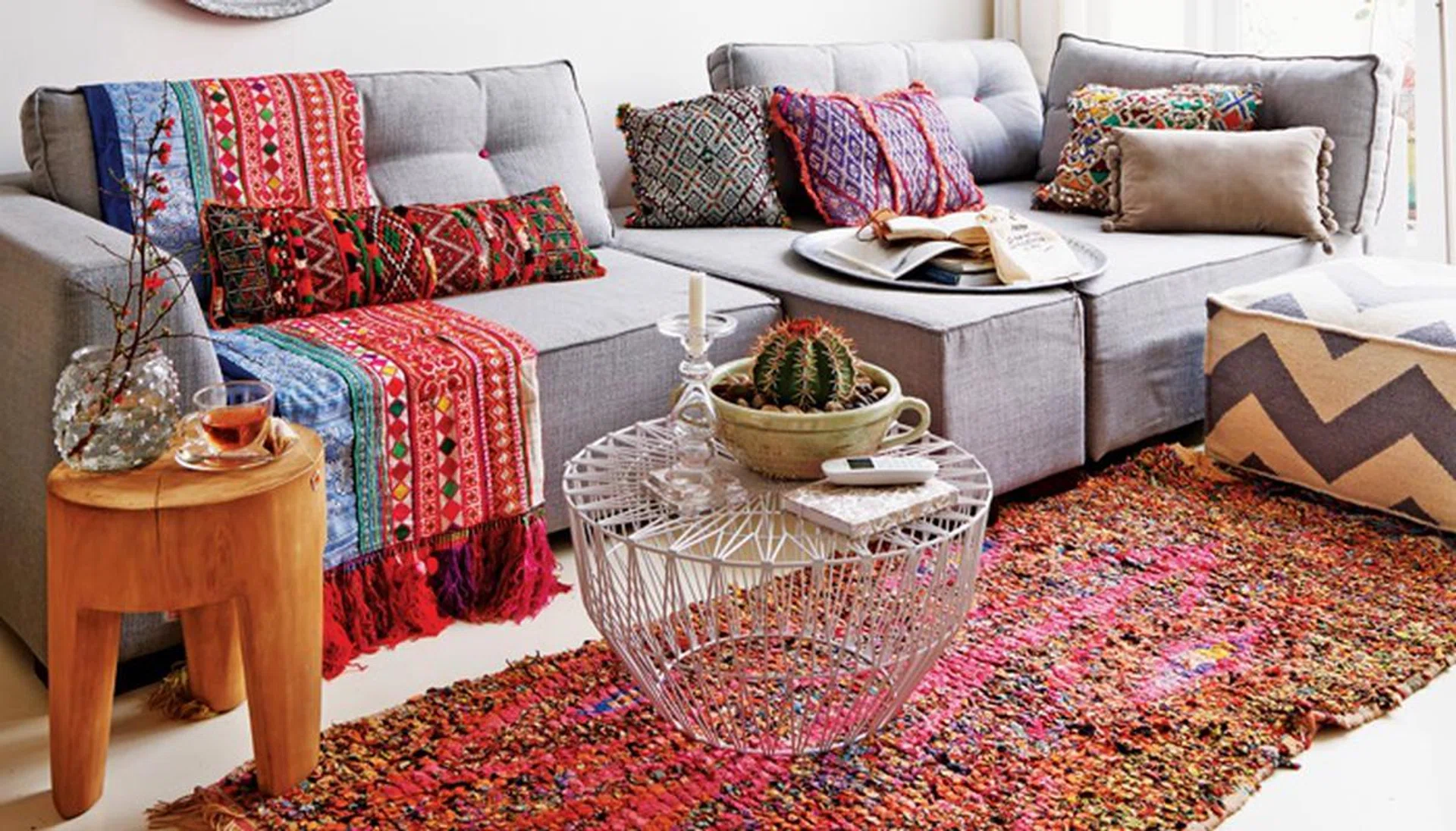 Oriental atmosphere with colourful fabrics, grey sofa set, metal trays on wall and typical Moroccan pendant lamps