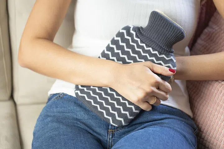 Caucasian woman having painful period cramps with hot water bottle