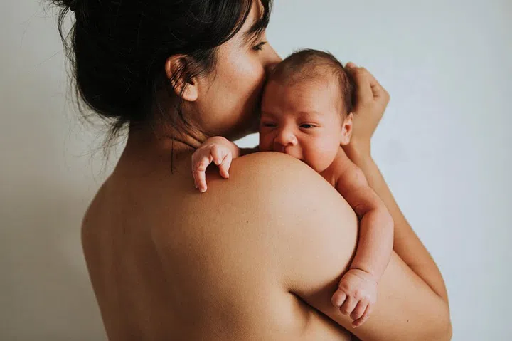 Naked mother holding her infant baby