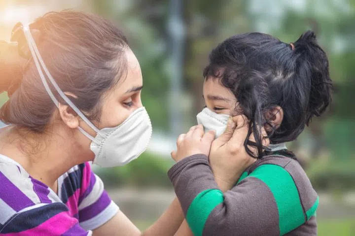 Covid-19 Coronavirus and Air pollution pm2.5 concept. Little Indian baby girl and mother wearing mask in public crowded place for protect and to stop corona virus outbreak