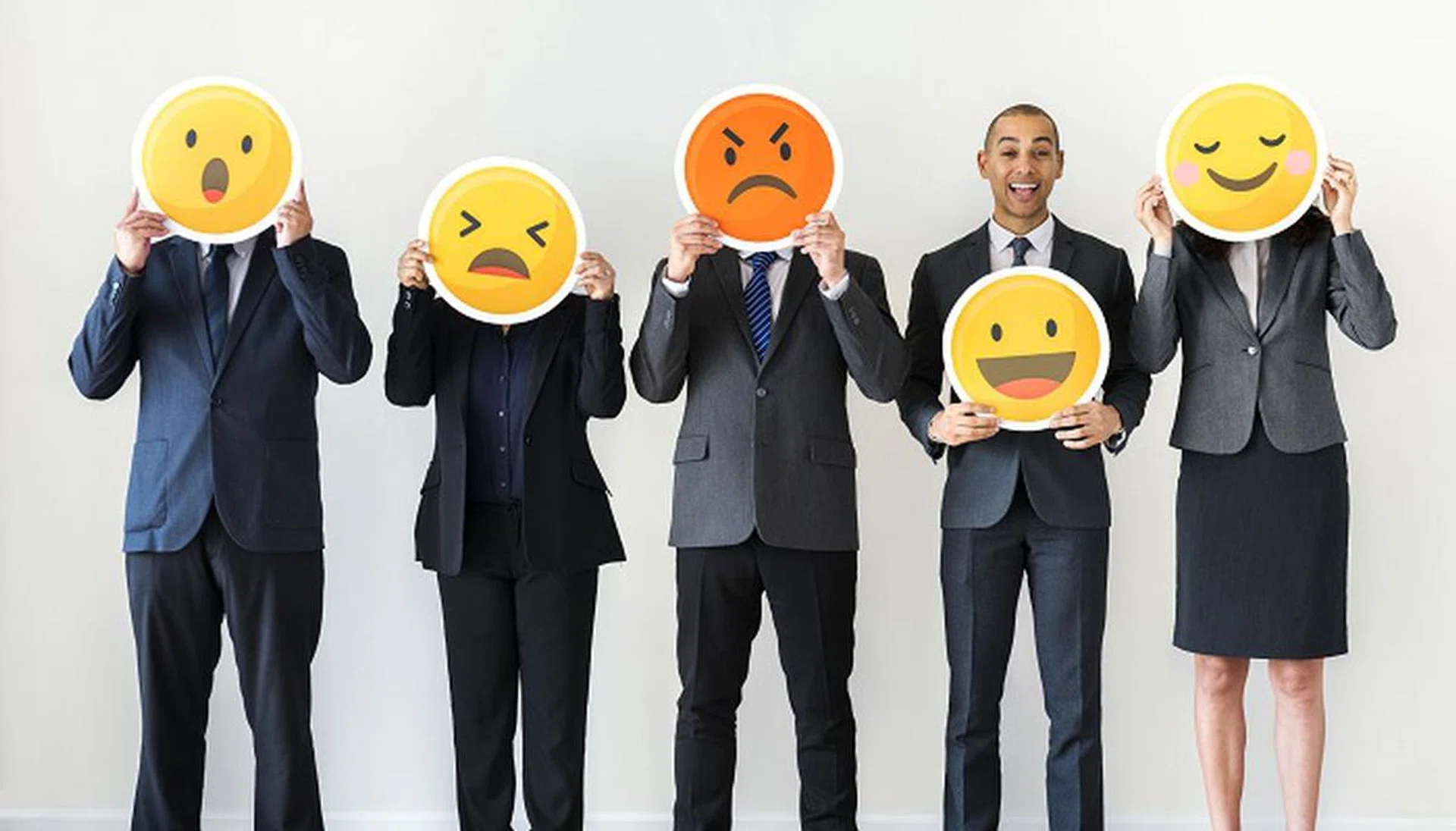 Business people standing and holding emoji icons