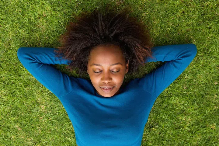 Portrait from above of a young african woman lying on grass sleeping
