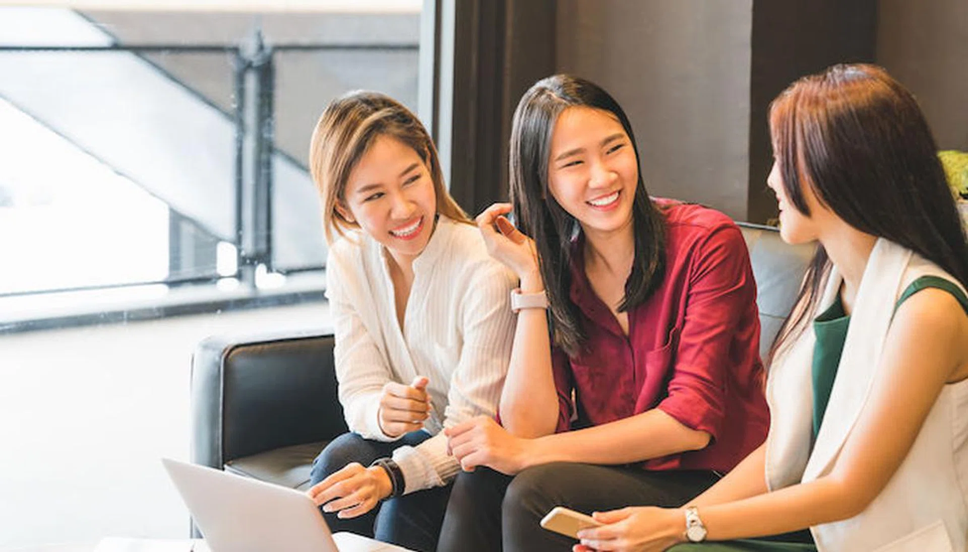 Three beautiful Asian girls chatting on sofa at cafe or coffee shop together. Gossip talks, Casual lifestyle with gadget technology, startup SME, college students or working business woman concept