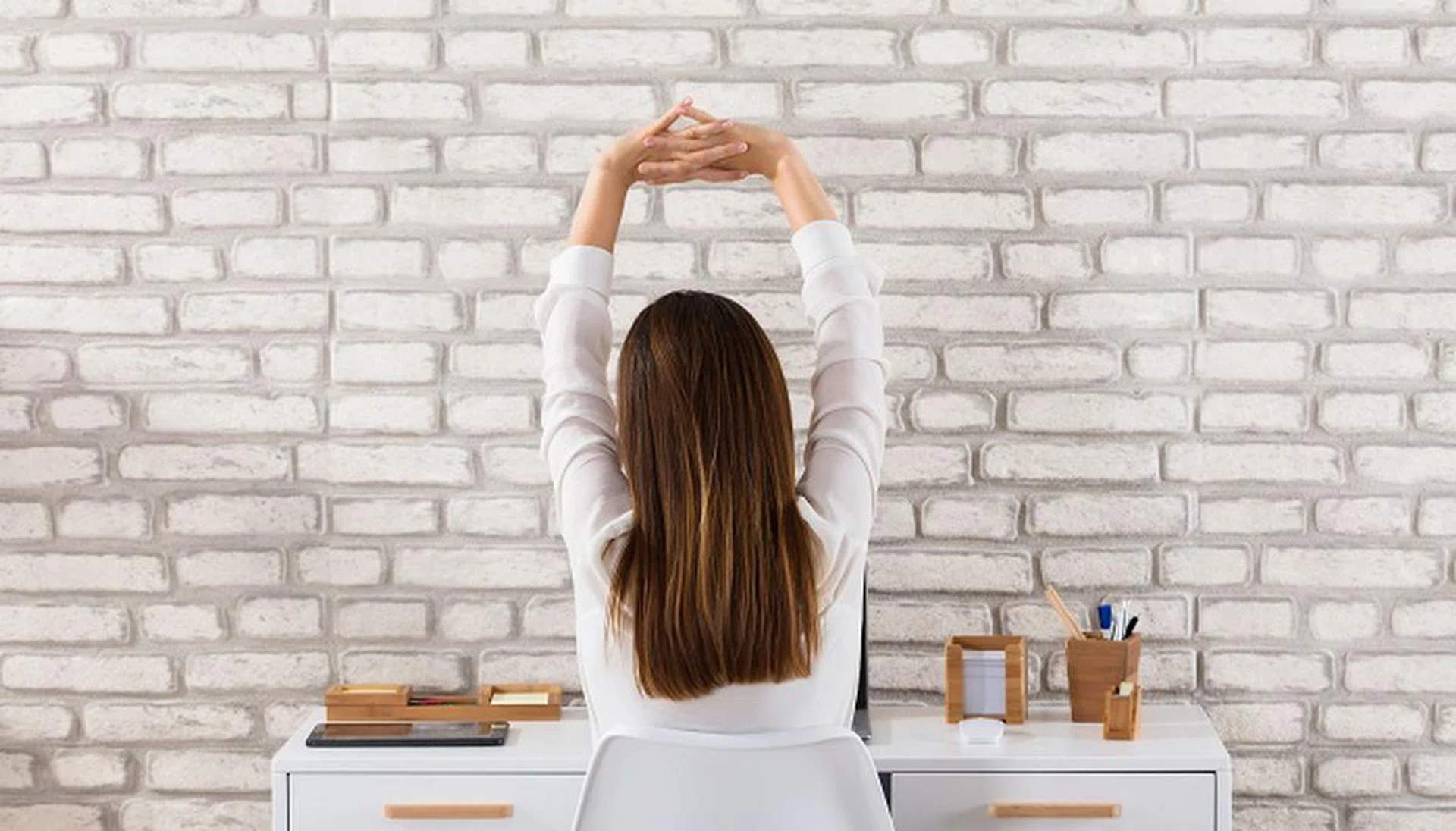 Rear View Of A Young Businesswoman Sitting On Chair Stretching Her Arms