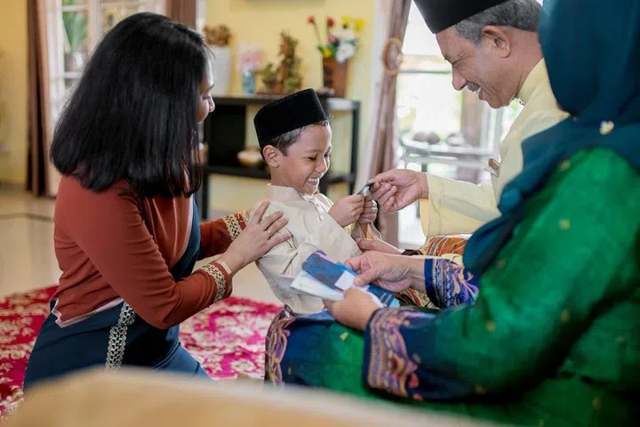 Young boy being presented with a gift of money from his grandparents as part of the Islamic celebration of Hari Raya Aidilfitri (Eid al-Fitr). Kuala Lumpur, Malaysia. May 2018