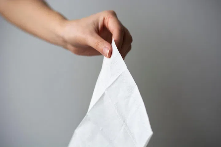A female hand holding a white clean tissue paper