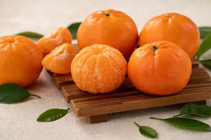 Fresh juicy small tangerine mandarin orange in a plate on white table background.